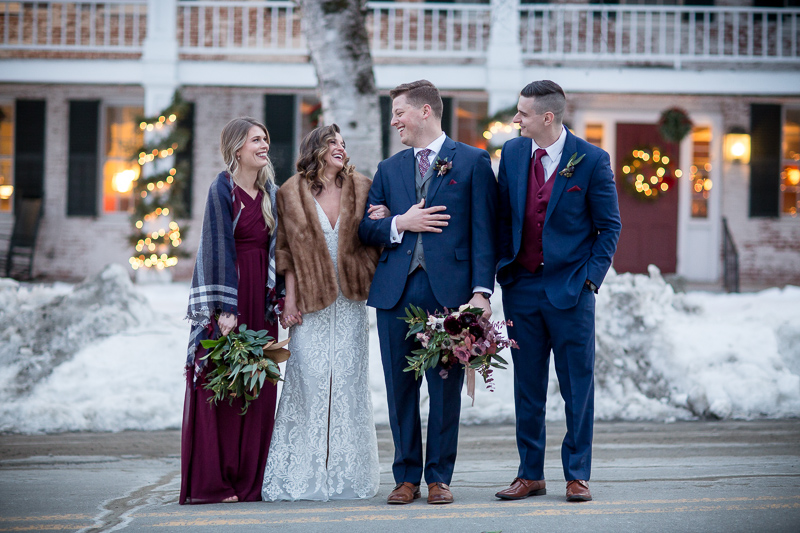 A bride and groom with their bestman and maid of honor stand out front of the Grafton Inn on a cozy winter afternoon