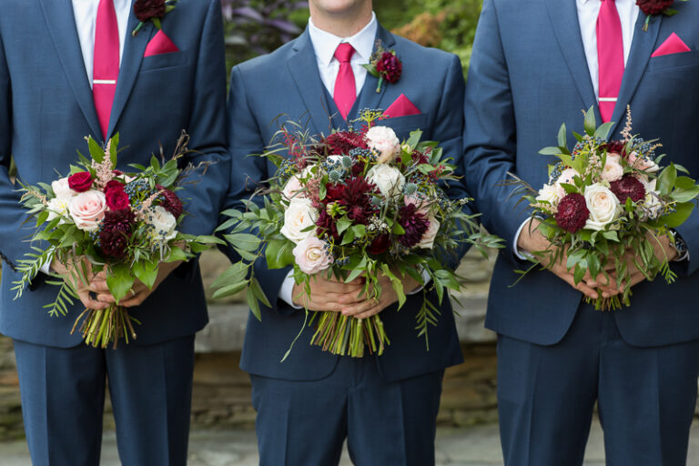 Groomsman hold the bridal bouquets in the park next to the green mountain inn in Stowe, Vermont