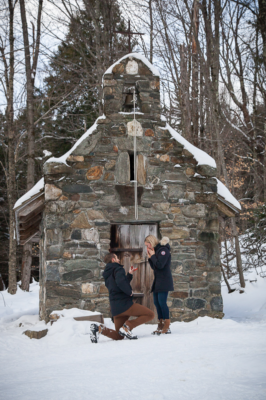 A young couple getting engaged in front of the chapel at the Trapp Family Lodge