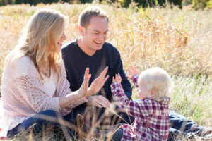 family plays patty cake in a sun kissed field at the Ethan Allen Homestead in Burlington, Vermont