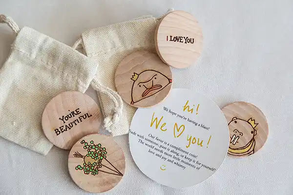 Complement coins displayed on wedding reception tables encouraging guests to share kind words at Vermont fall wedding.