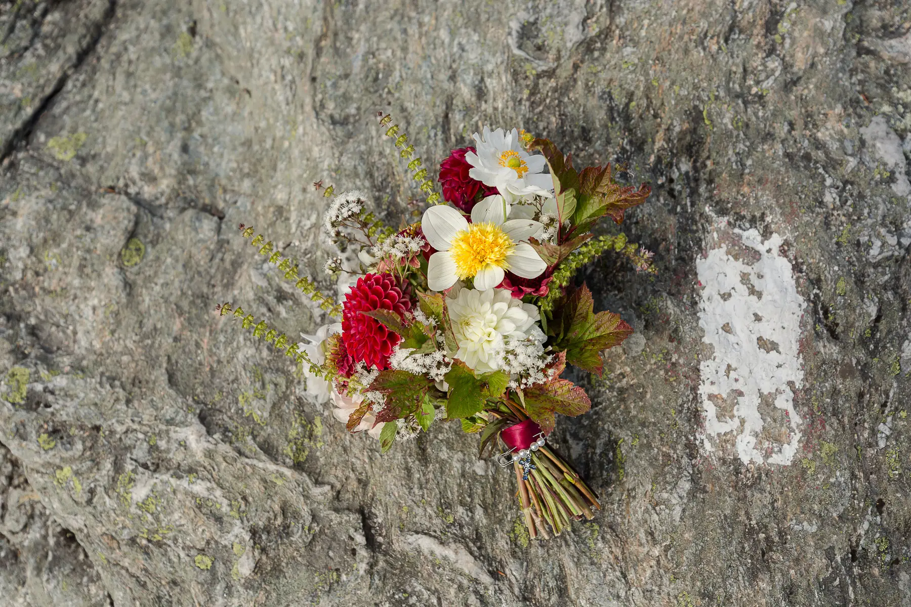 A bridal bouquet next to the long trail white trail blaze marker on top pf Mount Mansfield.