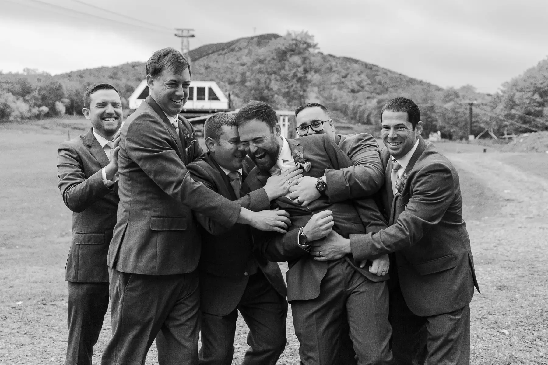 The groomsmen hug the groom below the Jay Peak Triple Chairlift