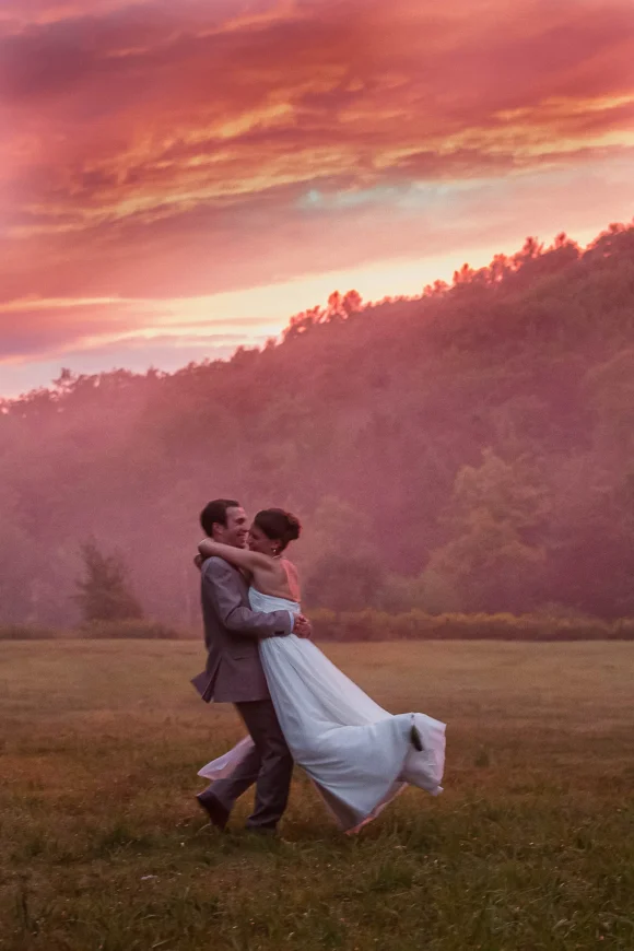 A bride and groom dance in the red sky at night sunset after their rainy Vermont wedding day