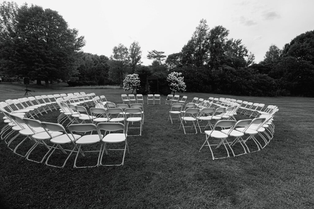 empty white folding chairs set up for a wedding ceremony in the round