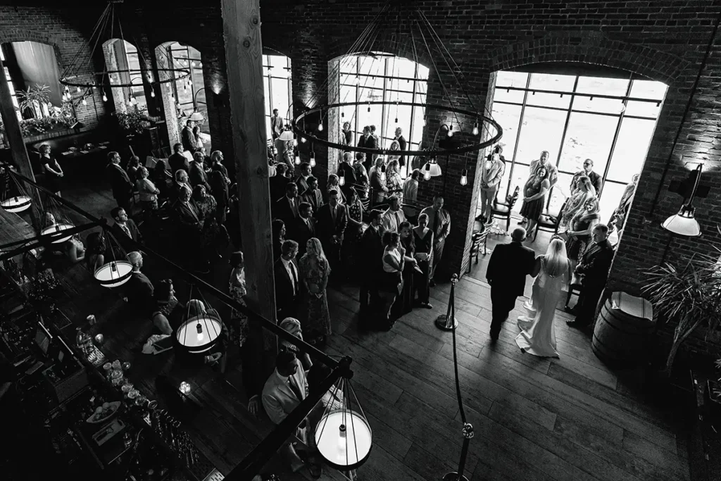 A view from the upper balcony, Dad walks his daughter down the aisle at Waterworks Restaurant Vermont