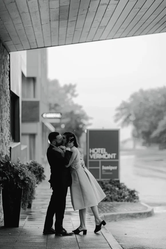 A couple kisses in the rain outside of Hotel Vermont just after their elopement