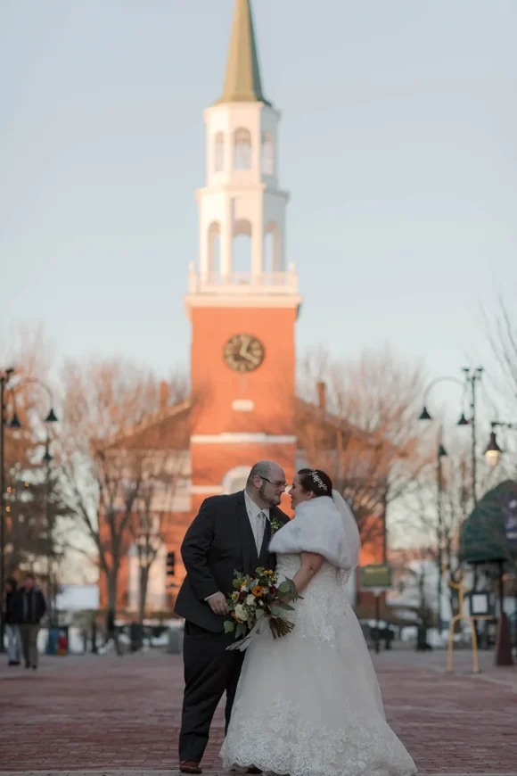 A wedding couple kisses on Church Street Burlington. It's late fall with no leaves on the trees