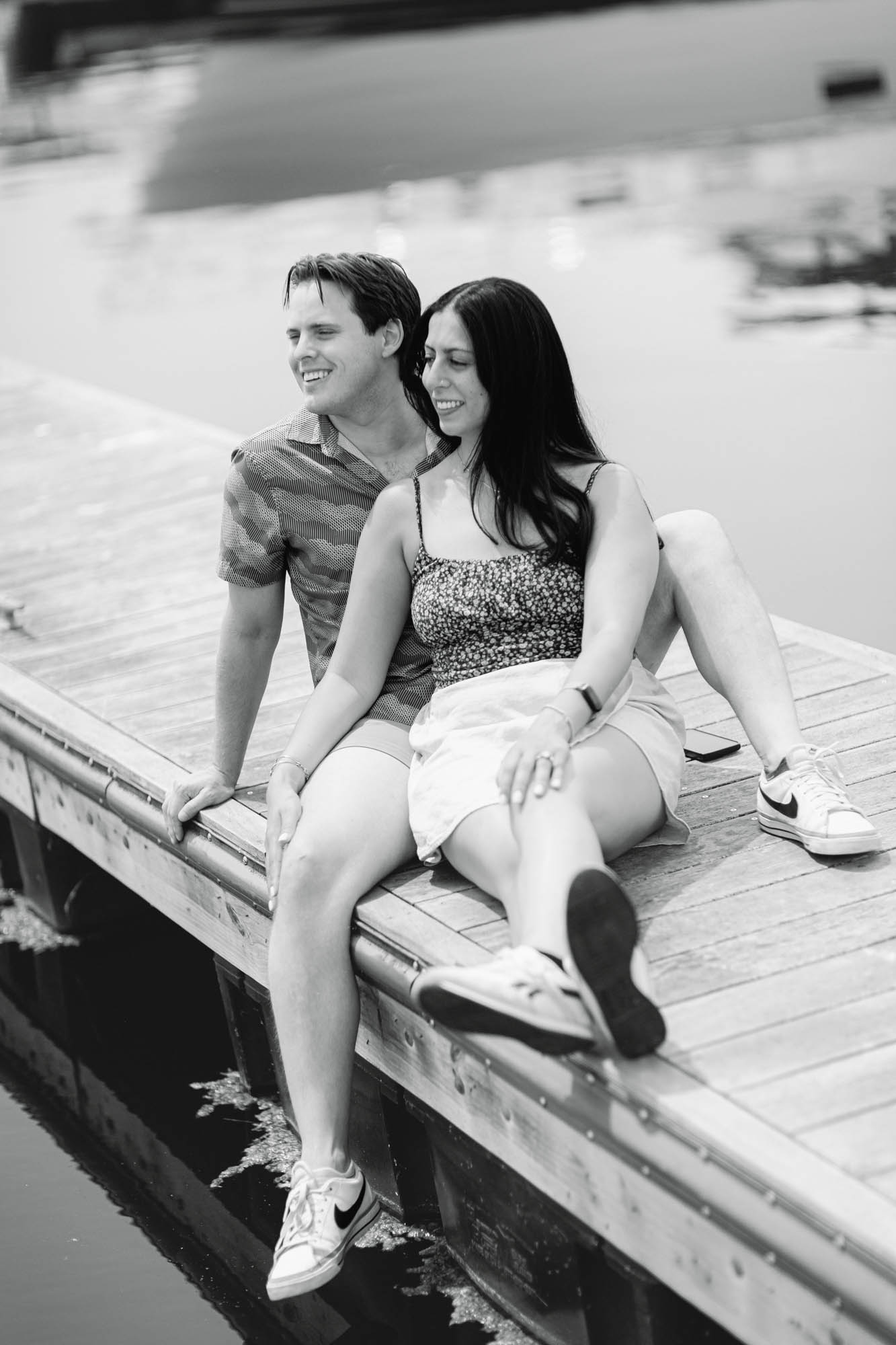 a black and white image of a couple chillin' on the dock