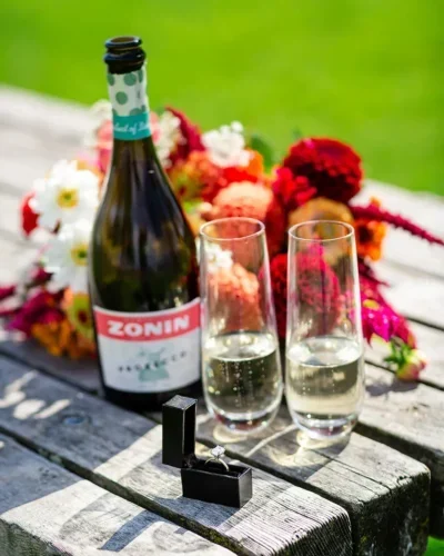 a bottle of champagne and an engagement ring on a table
