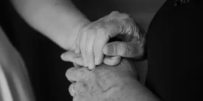 Bride's mother holds her hands in a tender getting ready moment while her sister fastens her wedding dress at Jay Peak Resort Vermont fall wedding.