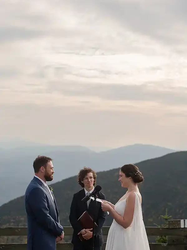 Couple exchanges vows at Jay Peak Resort summit ceremony as sunlight breaks through clouds during Vermont fall wedding.
